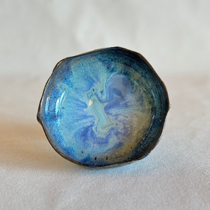 Ceramic bowl with blue and black marbled pattern on a white background