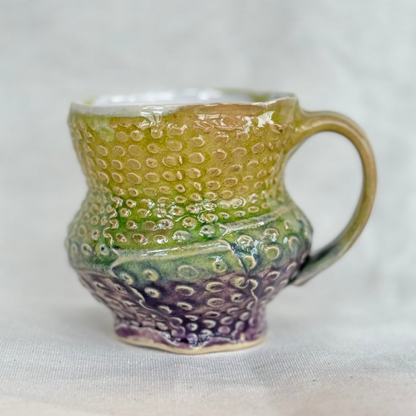 Handmade ceramic mug with textured design on a white background
