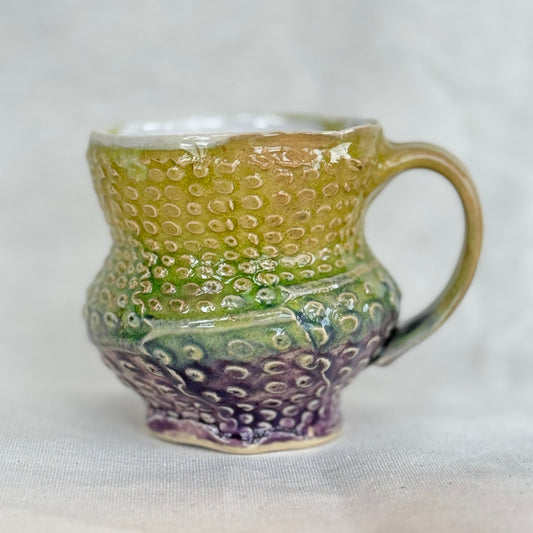 Handmade ceramic mug with textured design on a white background