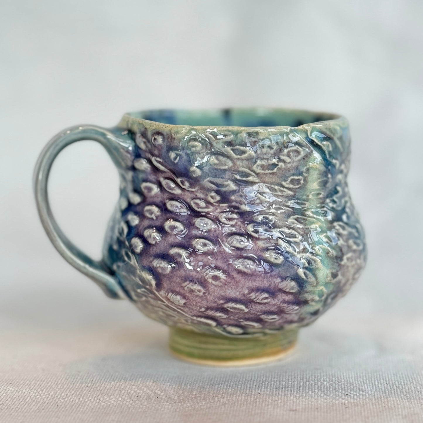 Handmade ceramic mug with textured surface on a white background