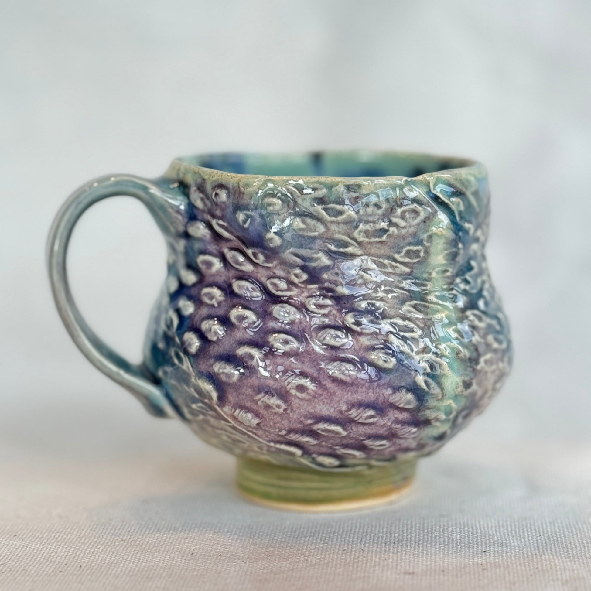 Handmade ceramic mug with textured surface on a white background