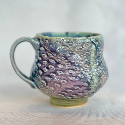 Handmade ceramic mug with textured surface on a white background