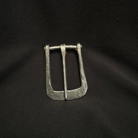 Silver belt buckle on a black fabric background