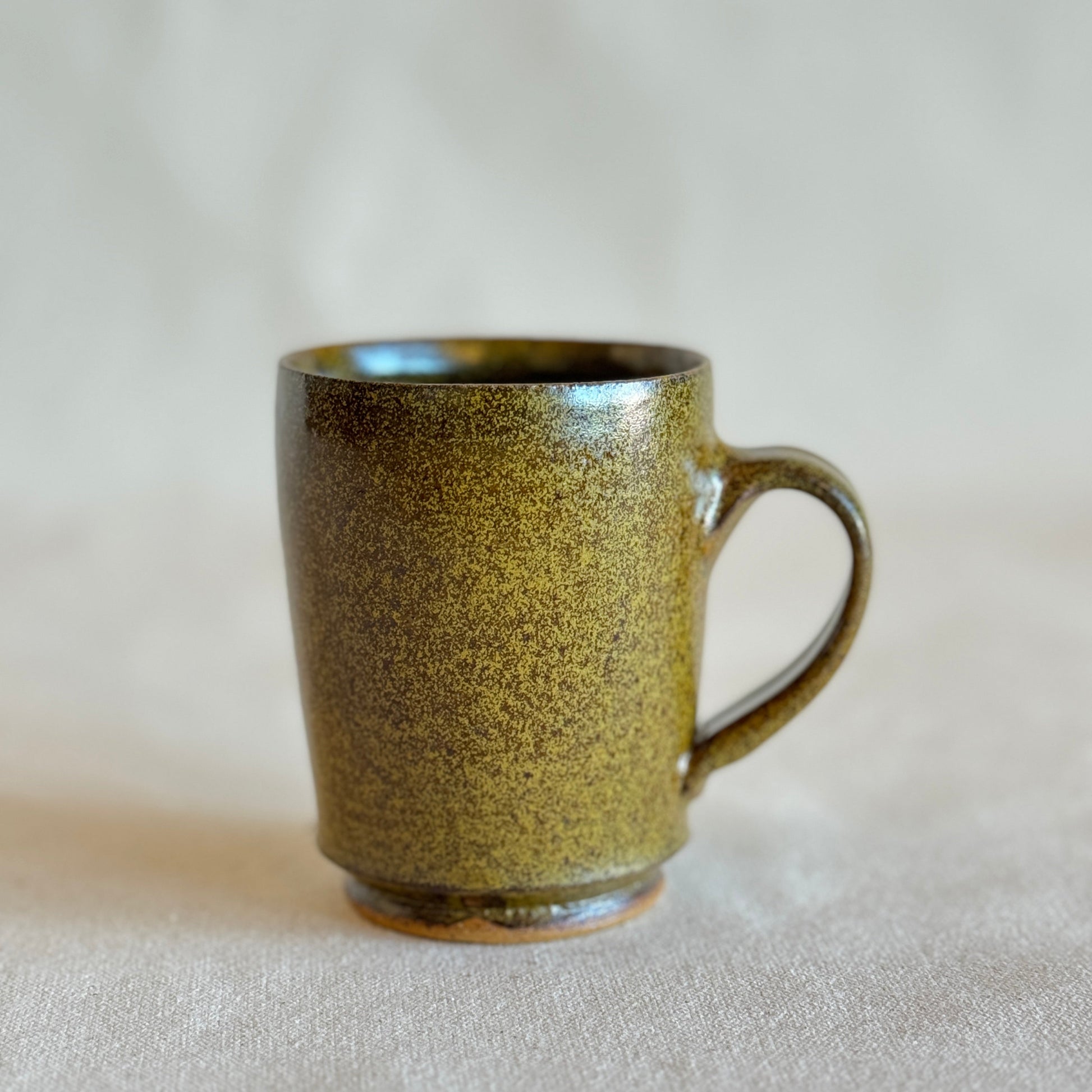 Green ceramic mug on a beige background