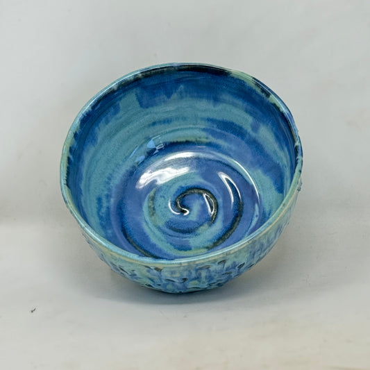 Blue ceramic bowl with a swirling pattern on a white background