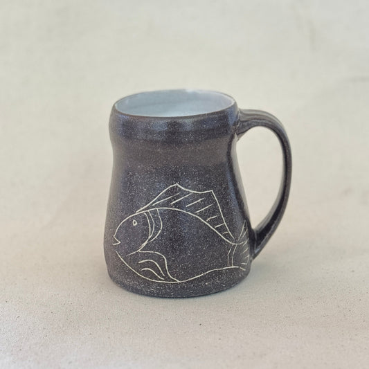 Ceramic mug with fish design on a light gray background