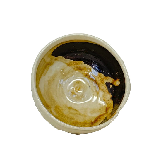 Close-up of a bowl with a swirl of cream on a white background