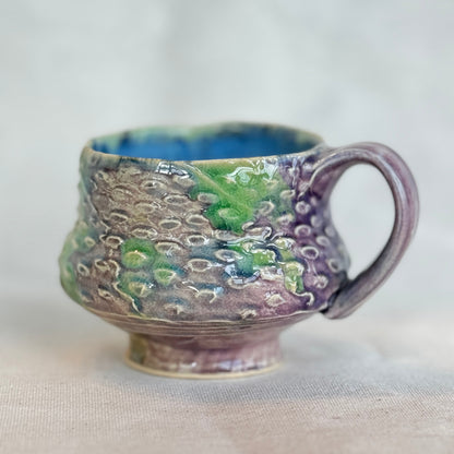 Handmade ceramic mug with textured surface on a light background