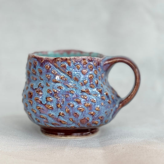 Ceramic mug with textured surface on a light background