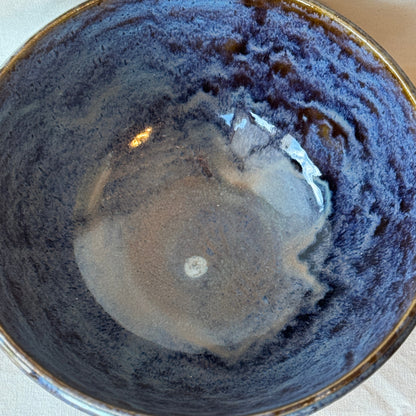 Close-up of a ceramic bowl with a dark, textured interior on a light background