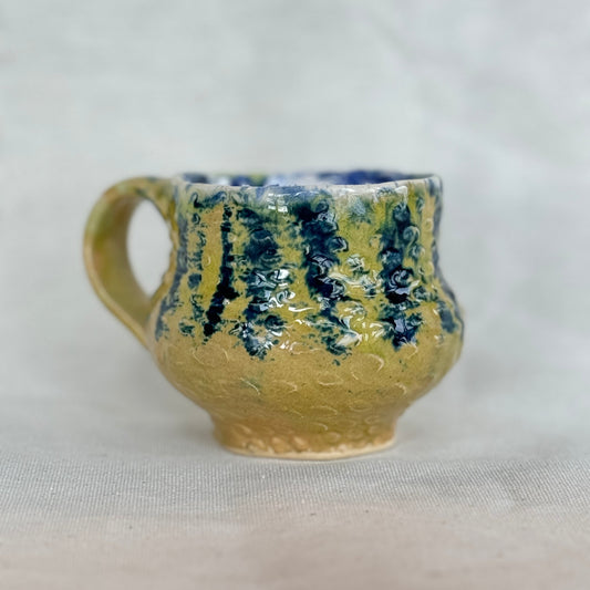 Ceramic mug with blue and green patterns on a white background