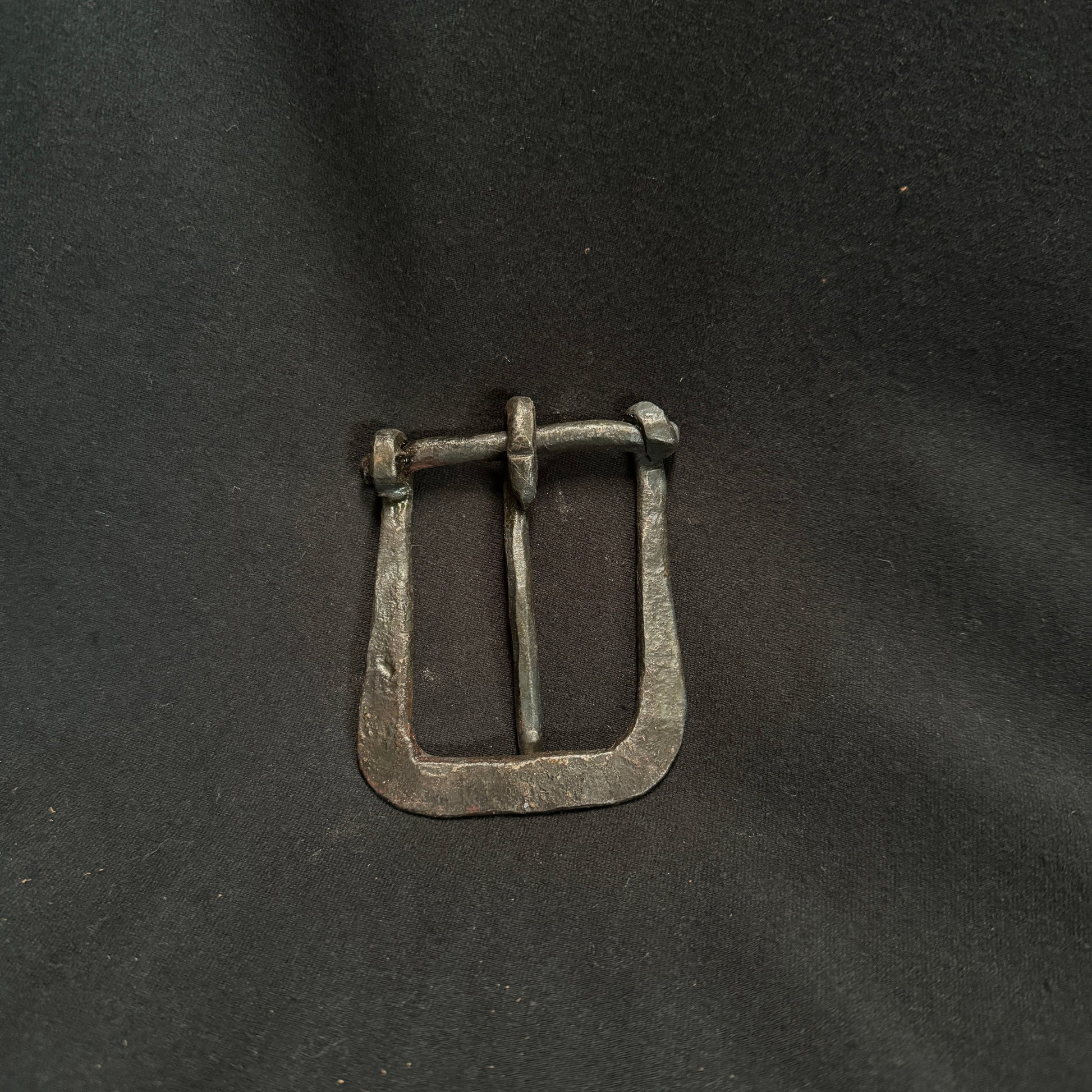 Silver belt buckle on a dark fabric background