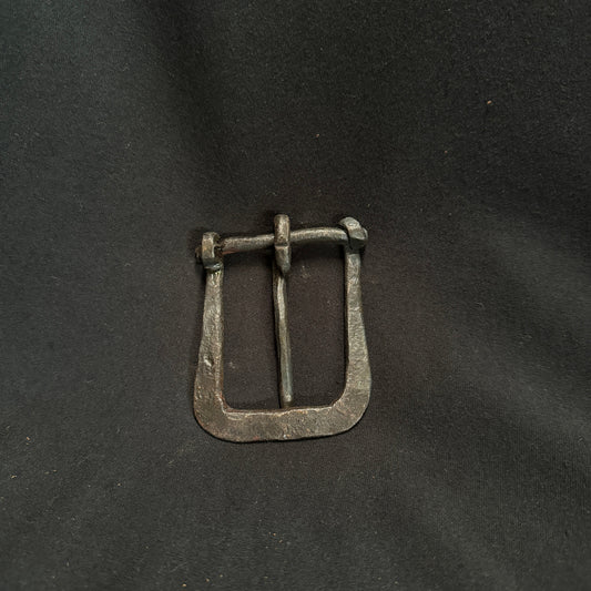 Silver belt buckle on a dark fabric background