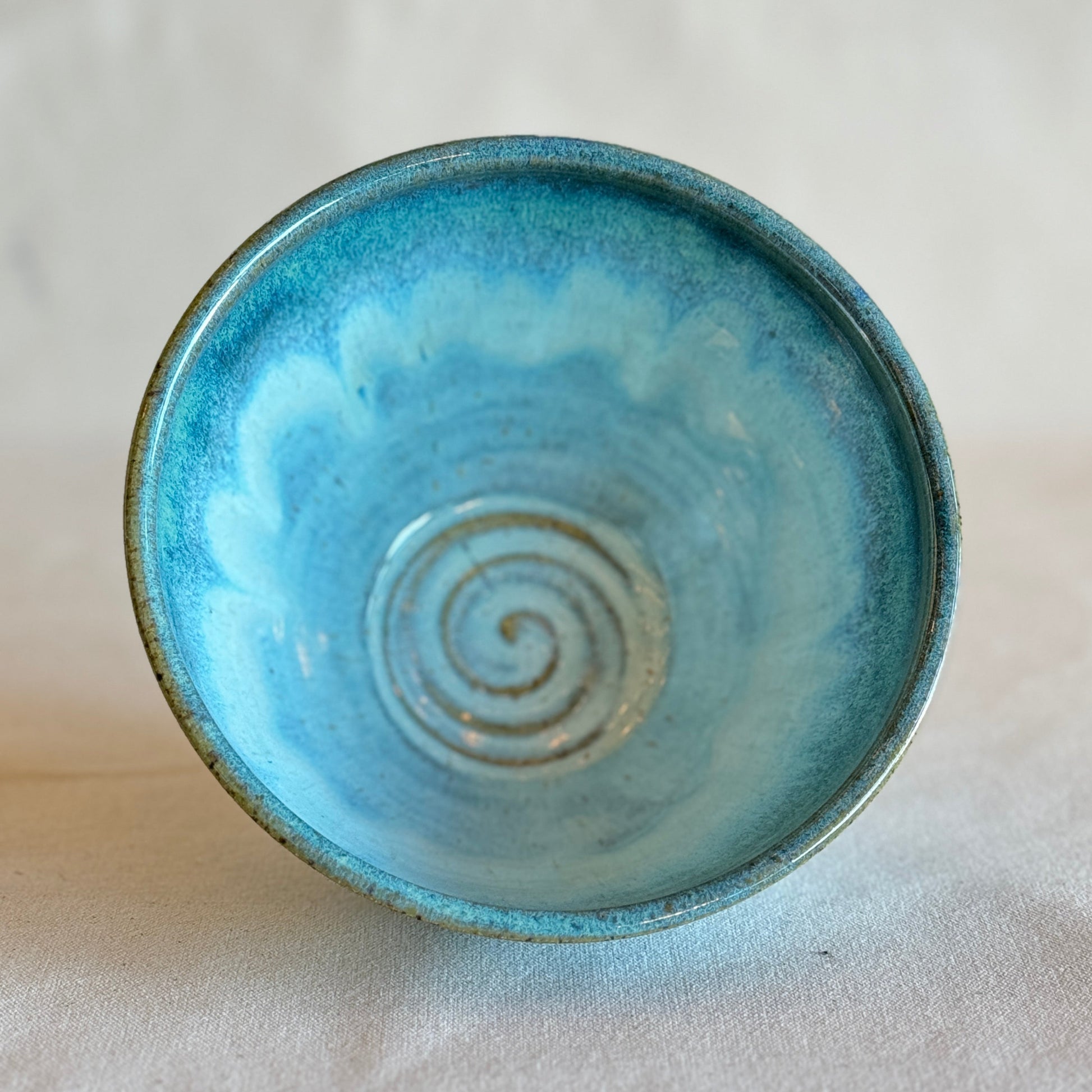 Blue ceramic bowl with a spiral design on a light gray background