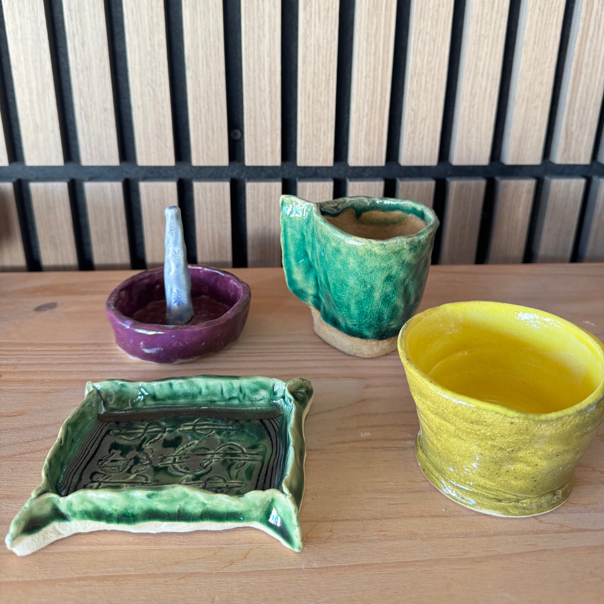 Four ceramic items on a wooden surface with a slatted wooden background