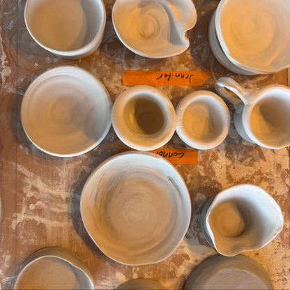Collection of ceramic bowls and cups on a wooden surface