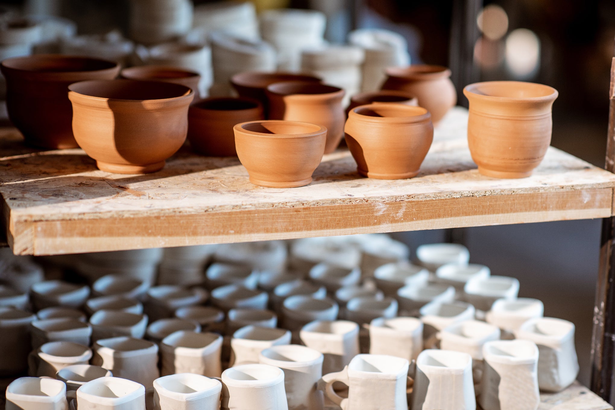 Collection of ceramic pots on a wooden shelf with a blurred background