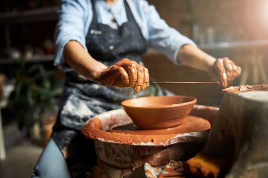 Person working with clay on a pottery wheel in a workshop setting