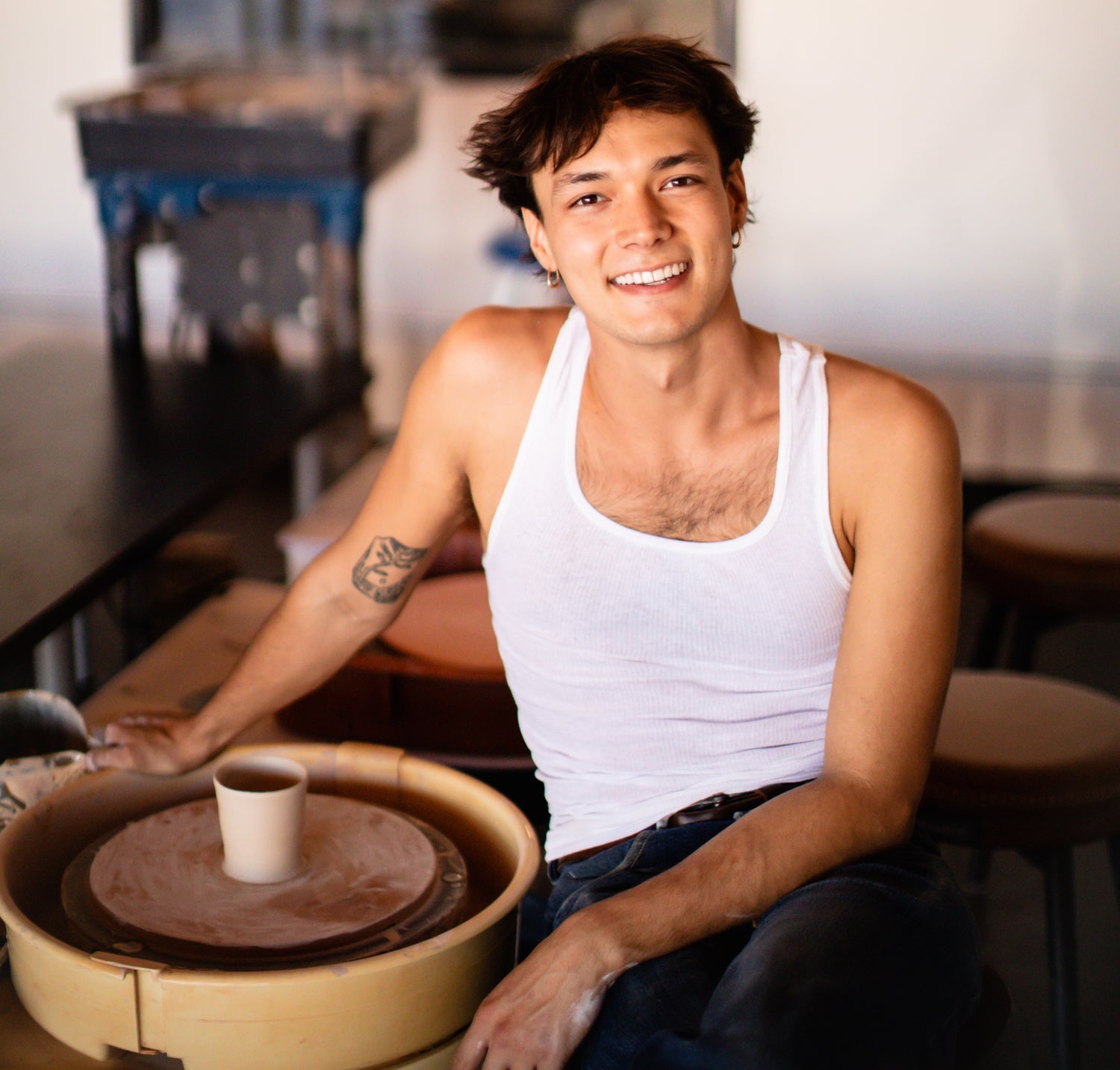 Person sitting at a pottery wheel in a studio
